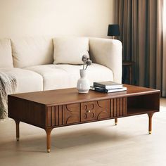 a living room with a couch, coffee table and books on the end tables in front of it