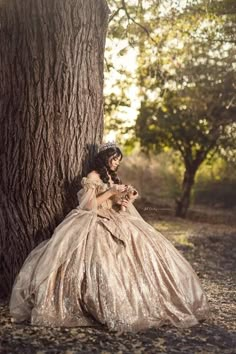 a woman in a dress sitting next to a tree