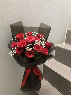 a bouquet of red roses sitting on top of a set of stairs with baby's breath