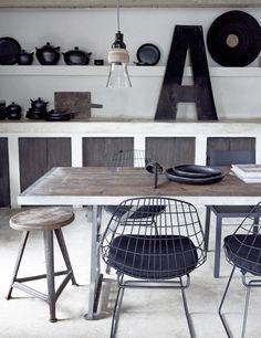 a dining room table with chairs and letters on the wall above it, along with two stools