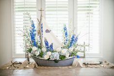 a sailboat with blue and white flowers is on display in front of the window