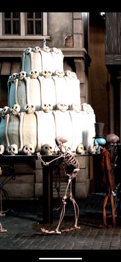 two skeletons are standing in front of a large stack of white cakes with skulls on them