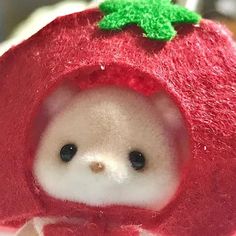 a small stuffed animal in a red strawberry hat