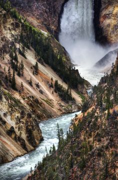 a large waterfall in the middle of a mountain with trees on it's sides