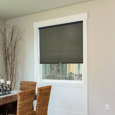 a dining room table with two chairs and a window covered in blind shades on the windowsill