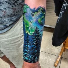 a man with a tattoo on his arm that has trees and stars in the sky