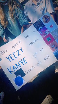 two young people holding up a sign that says yeezy kannye and smiles