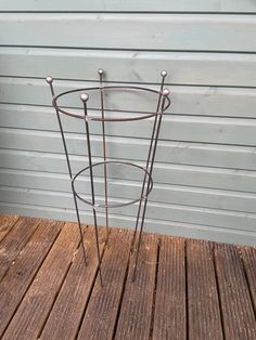 a metal plant stand sitting on top of a wooden deck