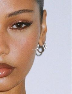 a close up shot of a woman's face with earrings on her ear and nose