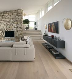 a living room filled with furniture and a stone wall next to a stair case in front of a flat screen tv