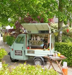 an ice cream truck parked on the side of a road next to bushes and trees