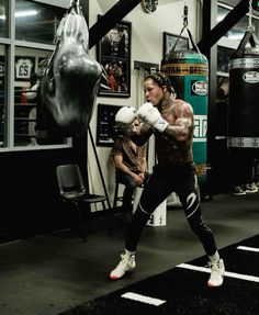 a man is practicing boxing in a gym with punching gloves on his chest and arm