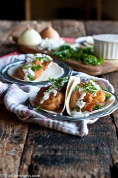 some tacos are sitting on a table next to an egg and other food items