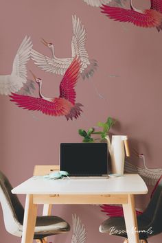 a laptop computer sitting on top of a wooden table next to two birds painted on the wall