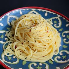 a blue and red plate topped with spaghetti