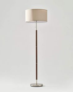 a floor lamp with a white shade on it's side and a wooden base