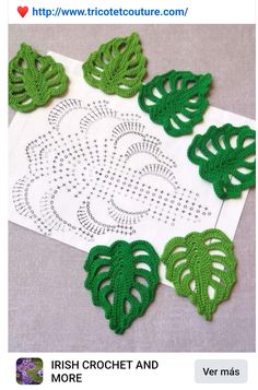 there are crocheted green leaves on the white doily that is next to each other