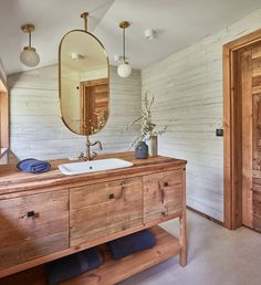 a bathroom with a wooden vanity and mirror above it is decorated in white wood planks