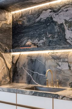 a kitchen with marble counter tops and white cabinets, along with gold faucets