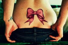 a woman's stomach with a pink bow tattoo on her belly and the bottom part of her lower body