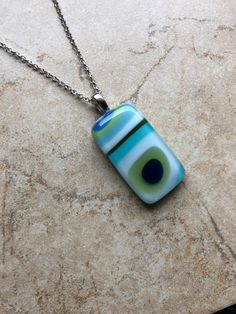 This is a fun, colorful, retro, mod fused glass pendant necklace, with  opalescent glass in  white, lime green, turquoise and blues.  The pendant is approximately .75" x 1.50" and comes on a 18" chain with lobster clasp. Caring for fused glass jewelry: To clean, use a soft cloth. Do not use harsh chemicals to clean. Should not be submerged in water, and should be removed when bathing. While fused glass is much stronger, use care when handling as can still break if dropped on hard surface.  Please contact me with any questions, changes or modifications.  Thank you so much for stopping at my shop! Fused Glass Jewelry Pendants, Modern Turquoise Glass Jewelry, Modern Blue Rectangular Necklace, Unique Green Necklace With Rectangular Pendant, Fused Glass Pendant Necklace, Fusing Glas, Fused Glass Necklace, Art Glass Jewelry, Glass Fusion