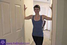 a woman standing in front of a door with her hands up to the ceiling and smiling