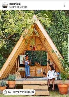 two children are standing on the roof of a small house made out of wooden planks