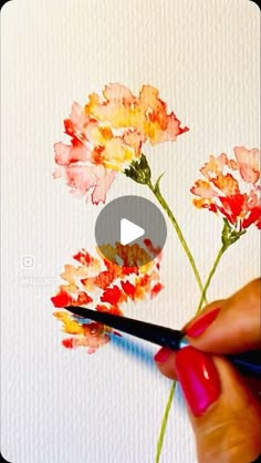 someone is painting flowers with watercolors on paper and using a brush to draw them