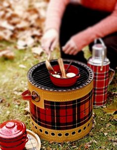 a man sitting on the ground next to two red and yellow picnic coolers with food in them