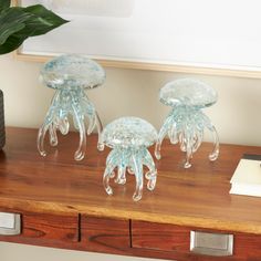 three glass jellyfish figurines sitting on top of a wooden table