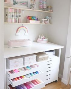 a white desk with lots of crafting supplies on it and shelves above the desk