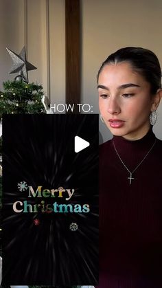 a woman standing in front of a christmas tree with the words merry christmas written on it