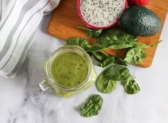 green smoothie with spinach and strawberries on cutting board next to fresh fruit