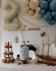 a table topped with cakes and cupcakes next to balloon shaped balloons in the shape of numbers