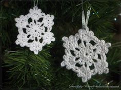 two crocheted snowflakes hanging from a christmas tree