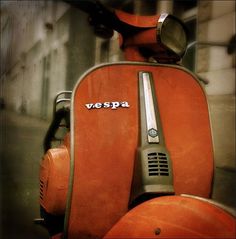 an orange scooter with the word vespa on it's seat