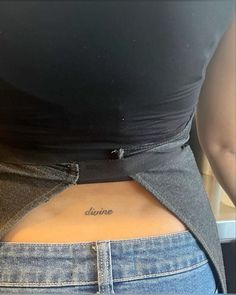 a woman's lower back tattoo with the word divine written on it