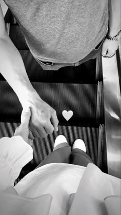 two people holding hands on an escalator with hearts in the air above them