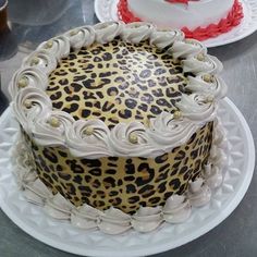 a leopard print cake sitting on top of a white plate next to a red and white cake