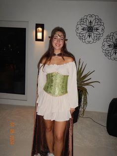 a woman in a costume standing next to a potted plant and smiling at the camera