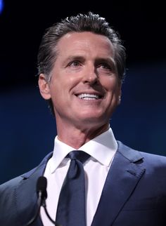 a close up of a person wearing a suit and tie with a microphone in front of him