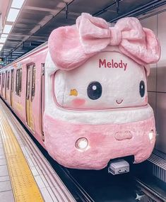 a pink hello kitty train with a bow on it's head at the station