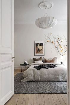 a bedroom with white walls and wood flooring has a large bed in the middle