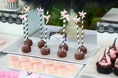 there are many desserts on the table with pink and black striped straws in them