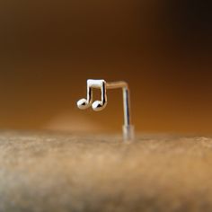 an earring with musical notes on it sitting on top of a piece of wood