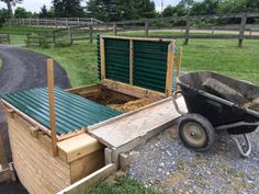 a wheelbarrow filled with dirt next to a wooden fence