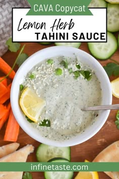 a white bowl filled with lemon herb tahini sauce surrounded by sliced cucumbers and carrots