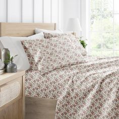 a bed with a white and red bedspread next to a window