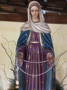 a statue of the virgin mary in purple and blue with chains around her ankles, holding two hands