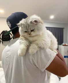 a man holding a cat in his arms and wearing a hat on top of his head